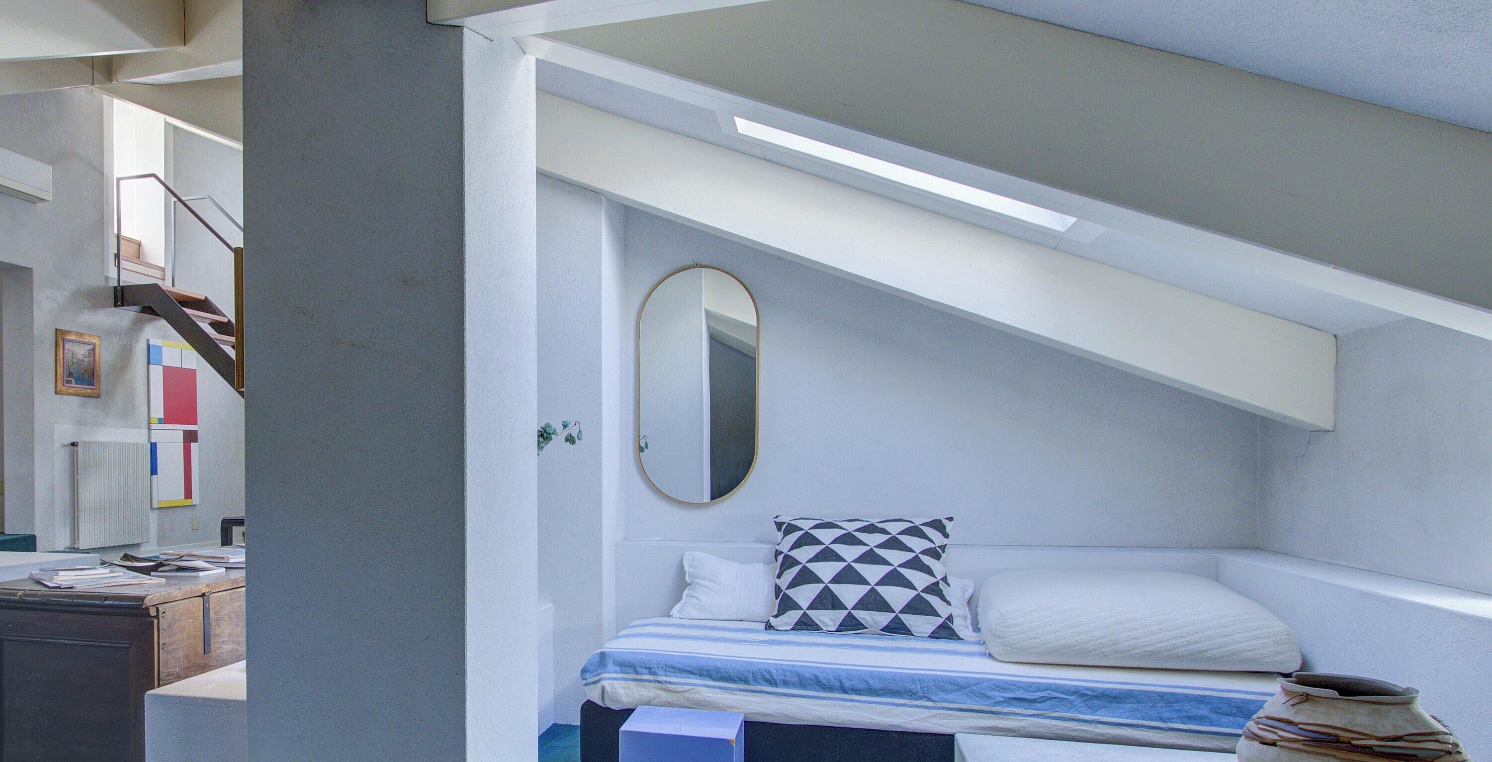 Une chambre à coucher avec un lit, un miroir et un bureau recouvert de papiers.