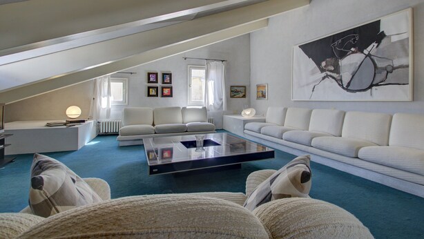 A modern loft-style living room with a glass coffee table, white sofas, and a large abstract painting on the wall. - ARNOLDI~Rooftop (Venezia)