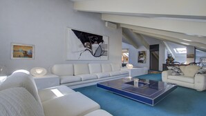 A modern living room with a sectional sofa, a coffee table, and artwork on the walls. - ARNOLDI~Rooftop (Venezia)