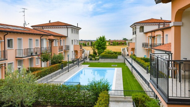 A residential building with a swimming pool, balconies, and a well-maintained lawn. - Aurora Home (Sirmione)