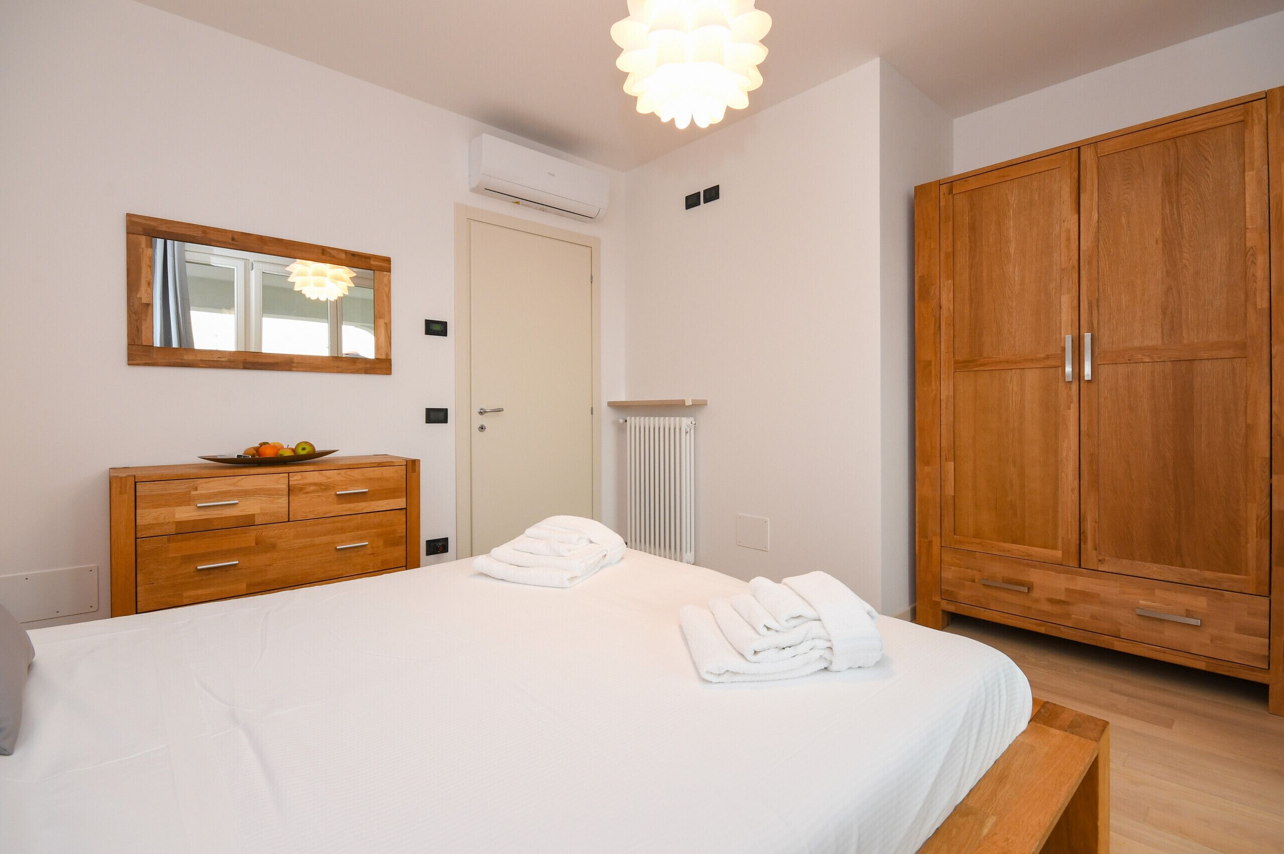 Une chambre à coucher avec un lit, une armoire en bois, un miroir et un radiateur.