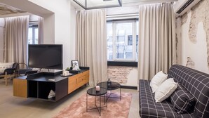 A modern living room with a flat-screen TV, a sofa, a coffee table, and a TV stand. - R34 Boutique Hotel (Sofia)