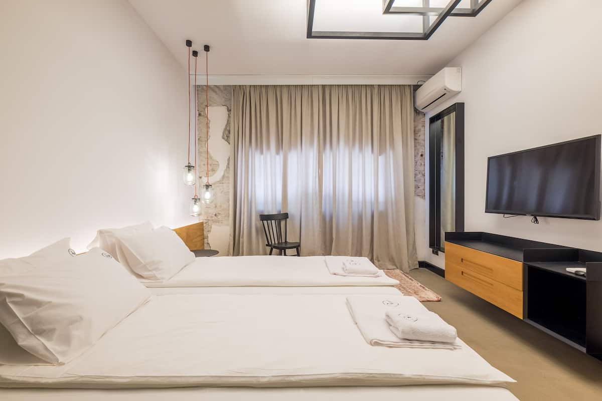Habitació d'hotel amb dos llits, televisió, escriptori i una cadira.