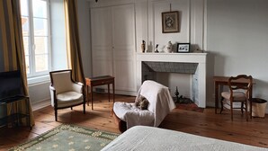 A room with a fireplace, a bed, a chair, a small table, and a television.