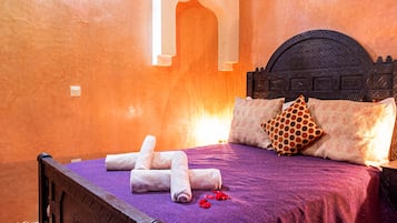 Una habitación con cama, almohadas, cabecero y alfombra.