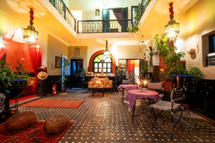 Um interior aconchegante com um piso estampado, uma área de estar com sofá e poltronas, e uma varanda com guarda-corrimão.
