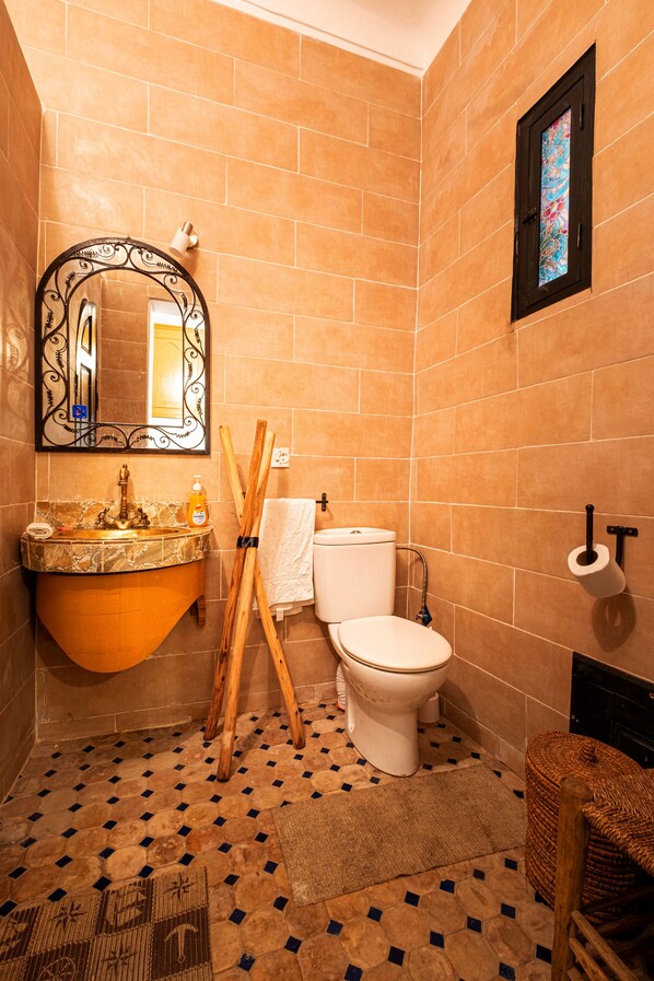 A bathroom with a marble sink, a toilet, and a mirror with an ornate frame. - Riad ViewPoint (Marrakech)