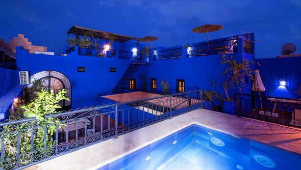 Een gebouw in blauwe tinten met een zwembad, terras en een trap.