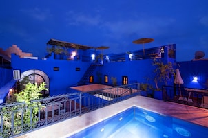 Um edifício azul com piscina, área de estar ao ar livre e escadaria.