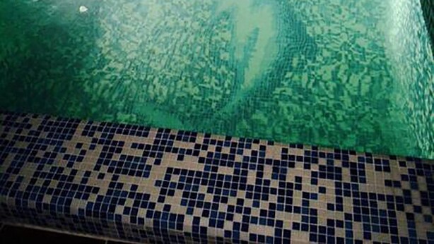 Una piscina cuadrada con borde de azulejos y superficie de agua cristalina.