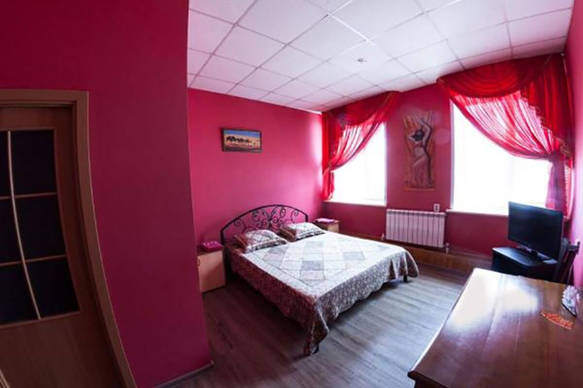 Un dormitorio con cama, escritorio y televisor.
