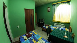 Una habitación con dos camas, un escritorio, una silla, un televisor y una ventana con cortinas.