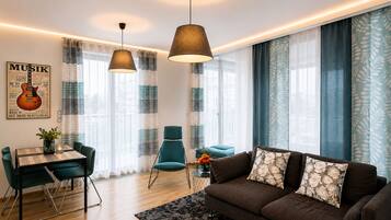 Una sala de estar moderna con sofá, mesa de comedor, sillas y lámparas colgantes.