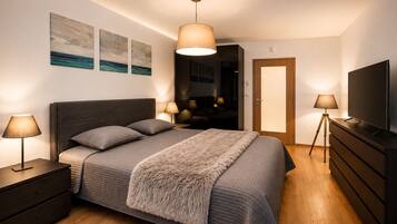 Un dormitorio con cama, lámparas de noche, televisión, cómoda y obras de arte en la pared.