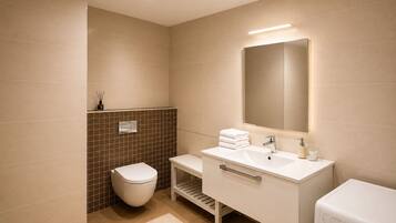 Un baño moderno con inodoro, lavamanos y espejo.