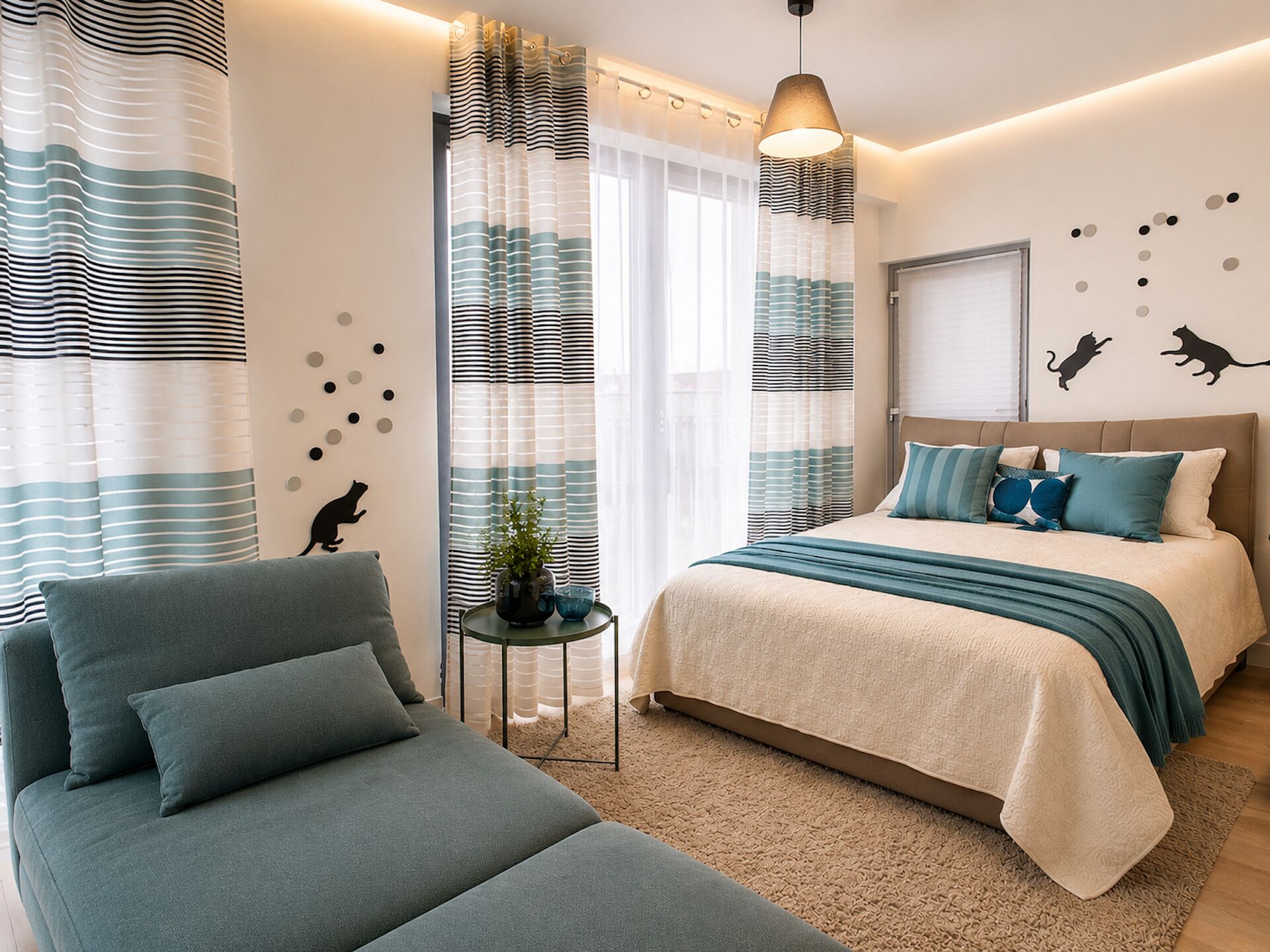 Une chambre à coucher comprenant un lit, un canapé, une petite table avec une plante et des œuvres d’art décoratives au mur.