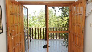 An open wooden door leading to a balcony with a tiled floor and a black cat lying on it. - Telemen'in Evi Pansiyon (Demre)
