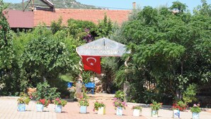 A garden with potted plants and a sign with Turkish flag and text. - Telemen'in Evi Pansiyon (Demre)