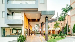 A modern hotel entrance with a covered walkway, outdoor seating, and a well-maintained garden. - Veredas Rio Quente (Rio Quente)
