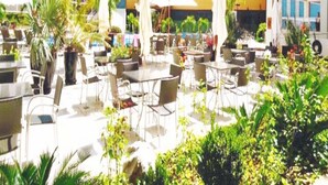 An outdoor patio area with multiple tables and chairs, surrounded by potted plants and umbrellas. - Veredas Rio Quente (Rio Quente)