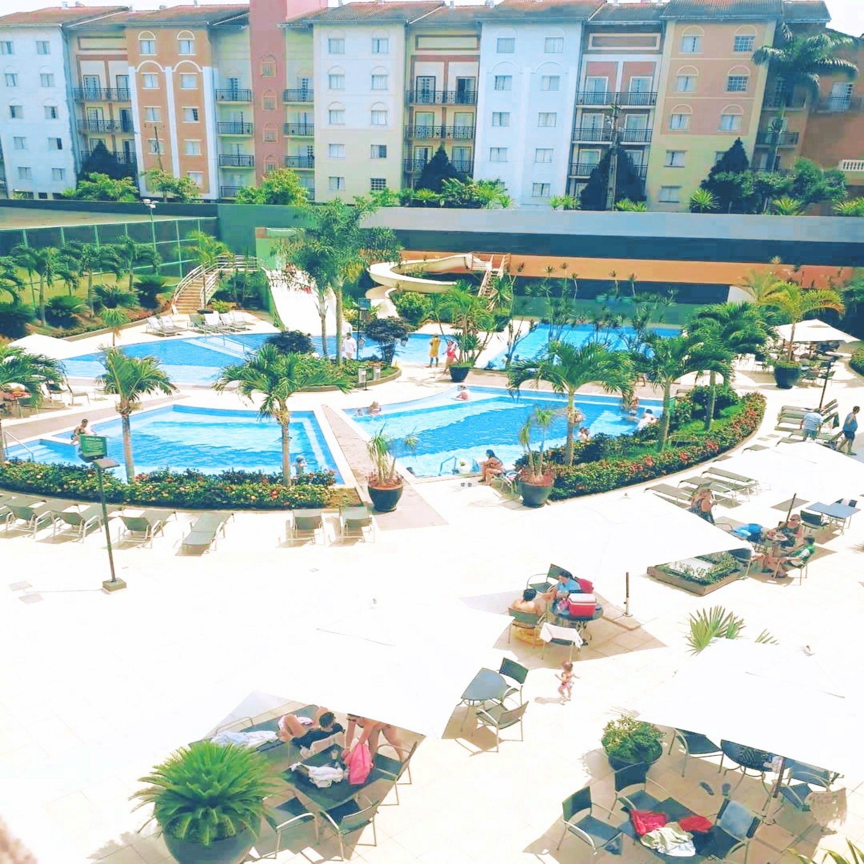 Resort com várias piscinas, áreas de descanso e diversos tipos de assentos.