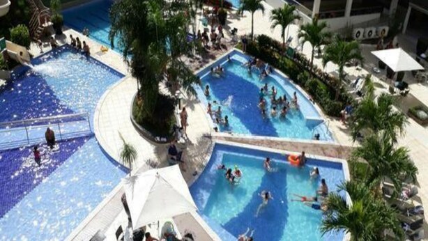 A multi-level pool area with various swimming pools, lounge chairs, and palm trees. - Veredas Rio Quente (Rio Quente)