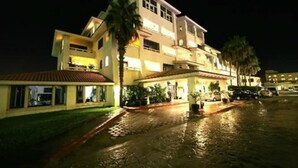 Un hotel de varios pisos con patio, palmeras y un camino pavimentado.