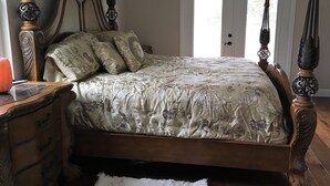 A bedroom with a wooden bed, floral bedding, a nightstand, and a dresser. - The Penthouse at Enchanted Acres Ranch (Cocoa)