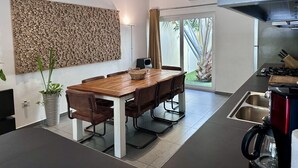 A modern kitchen with a wooden dining table, chairs, and a built-in stove.