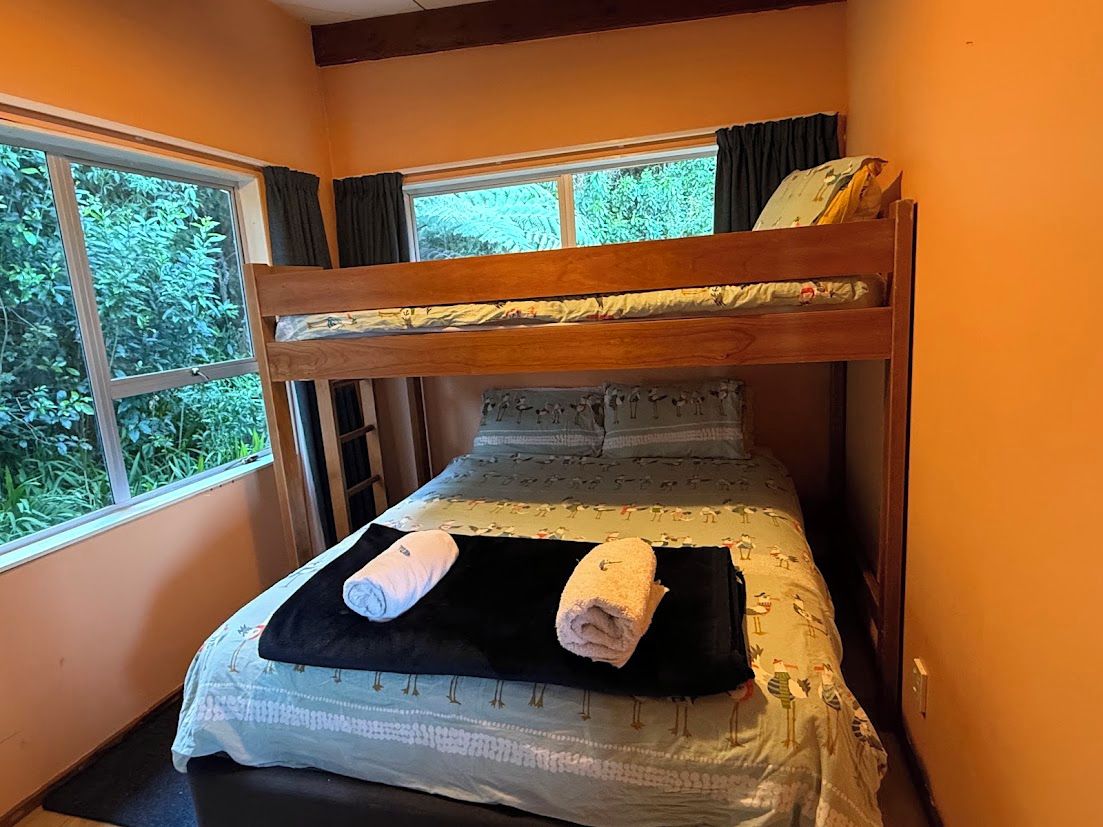 Una cama litera con ventana, un tapete negro y dos toallas enrolladas.