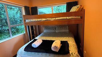Una cama litera con ventana, un tapete negro y dos toallas enrolladas.
