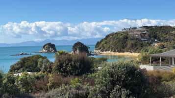 Eine Küstenlandschaft mit klarem Himmel, Felsformationen und einem Gebäude auf einem Hügel mit Blick aufs Meer.