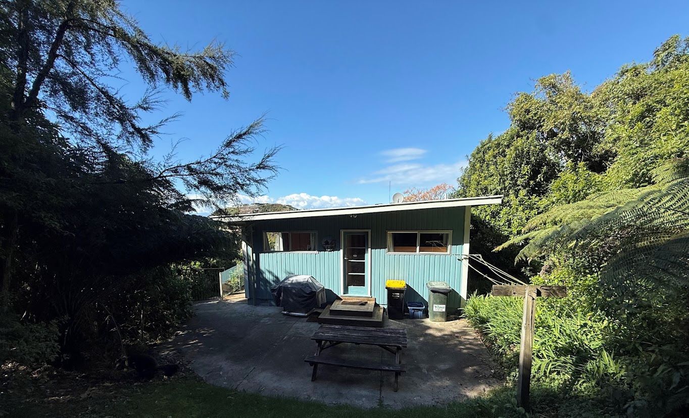 A house with a covered outdoor area, a wooden bench, and a pathway leading to the entrance.
