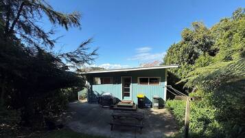 A house with a covered outdoor area, a wooden bench, and a pathway leading to the entrance.