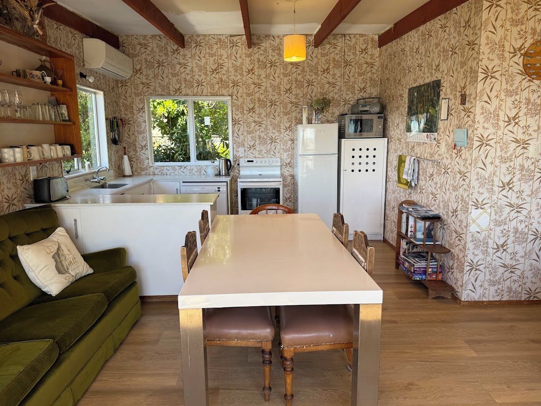 A compact kitchen with a dining table, a sofa, and a window.