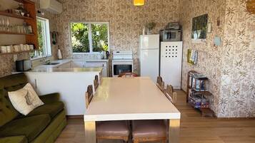 A compact kitchen with a dining table, a sofa, and a window.