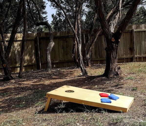 Un juego de mesa de madera montado al aire libre, sobre una mesa de madera y dos cojines.