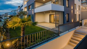 A modern multi-story residential building with balconies, a well-maintained garden, and a staircase leading to the entrance. - Villa Four Brothers - Exclusive Apartment (Podstrana)