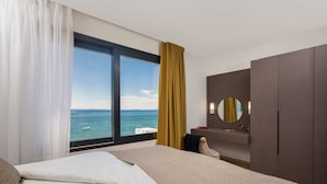 A hotel room with a bed, a large window with a view of the sea, a mirror, and a wardrobe. - Villa Four Brothers - Exclusive Apartment (Podstrana)