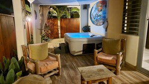 A cozy patio area with a hot tub, wooden furniture, and a mural on the wall. -  5 STAR BeachSide/Communal Pool/Private Spa/Terrace
NO CLEAN FEE Betwn Aug1-Nov1 (Ensenada)