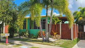 A building with a green facade, a wooden fence, and a street parking sign. -  5 STAR BeachSide/Communal Pool/Private Spa/Terrace
NO CLEAN FEE Betwn Aug1-Nov1 (Ensenada)