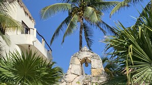 A gated area with palm trees, a stone archway, and a view of the ocean.