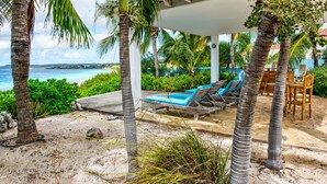 A beachside resort with a pool area, lounge chairs, and a view of the ocean.