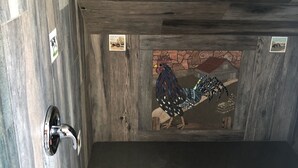 Kylpyhuone, jossa on puinen katto, laatoitettu lattia ja seinään kiinnitetty pesuallas.