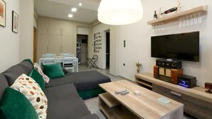 A modern living room with a sofa, coffee table, TV, and a wooden entertainment unit.