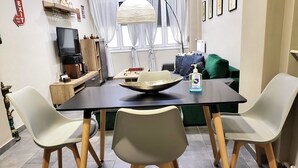 A dining area with a black table, two white chairs, a bowl, and a bottle of hand sanitizer.