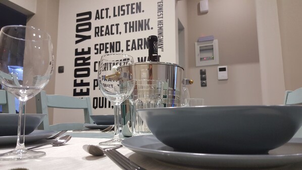 Une table dressée avec de beaux verres, des assiettes et des couverts, et une citation inspirante affichée sur le mur derrière.