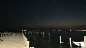 A nighttime view of a pier extending into a body of water with a boat docked at the end.