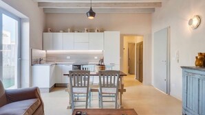 A modern kitchen with white cabinets, a dining area with two chairs, and a wooden table. - new apt with private garden, all comforts, WI-Fi & AC, in Salento's hearth (Diso)