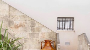 A pool area with a large vase, a lantern, and a staircase against a stone wall. - new apt with private garden, all comforts, WI-Fi & AC, in Salento's hearth (Diso)